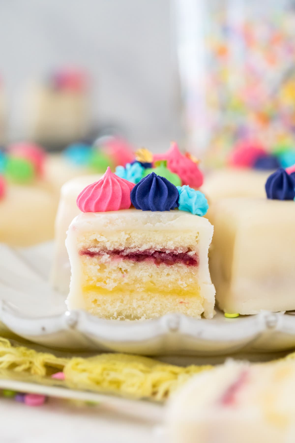 cross-section of petit four showing cake, lemon curd, and raspberry layers