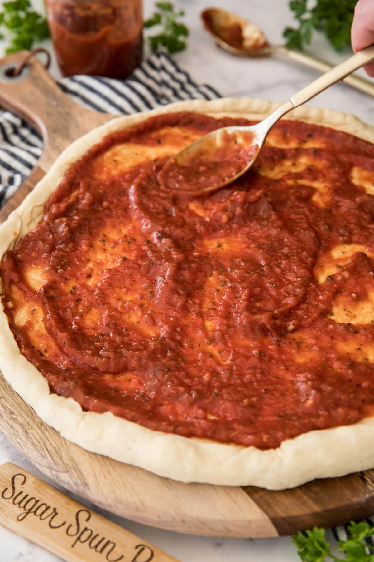 Spreading pizza sauce over pizza dough