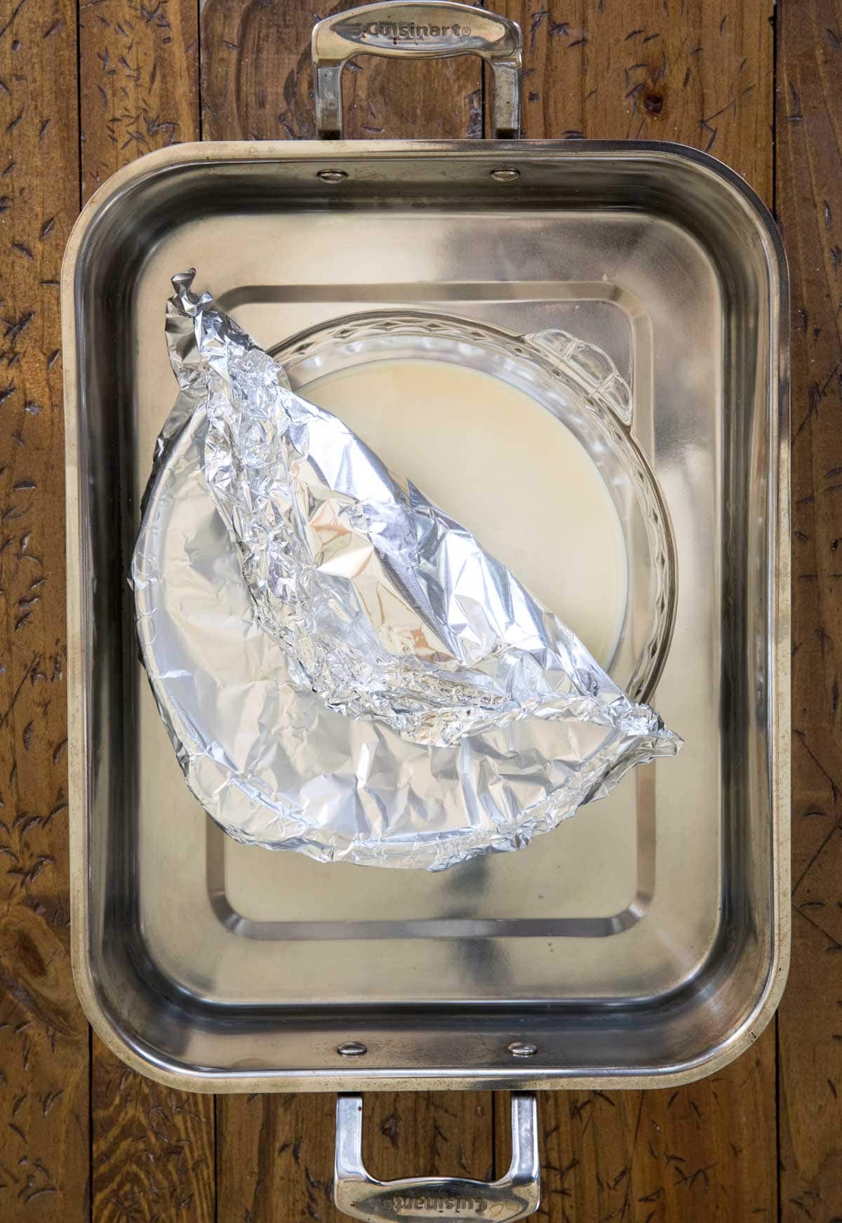 pie plate with condensed milk sitting in roasting pan with water