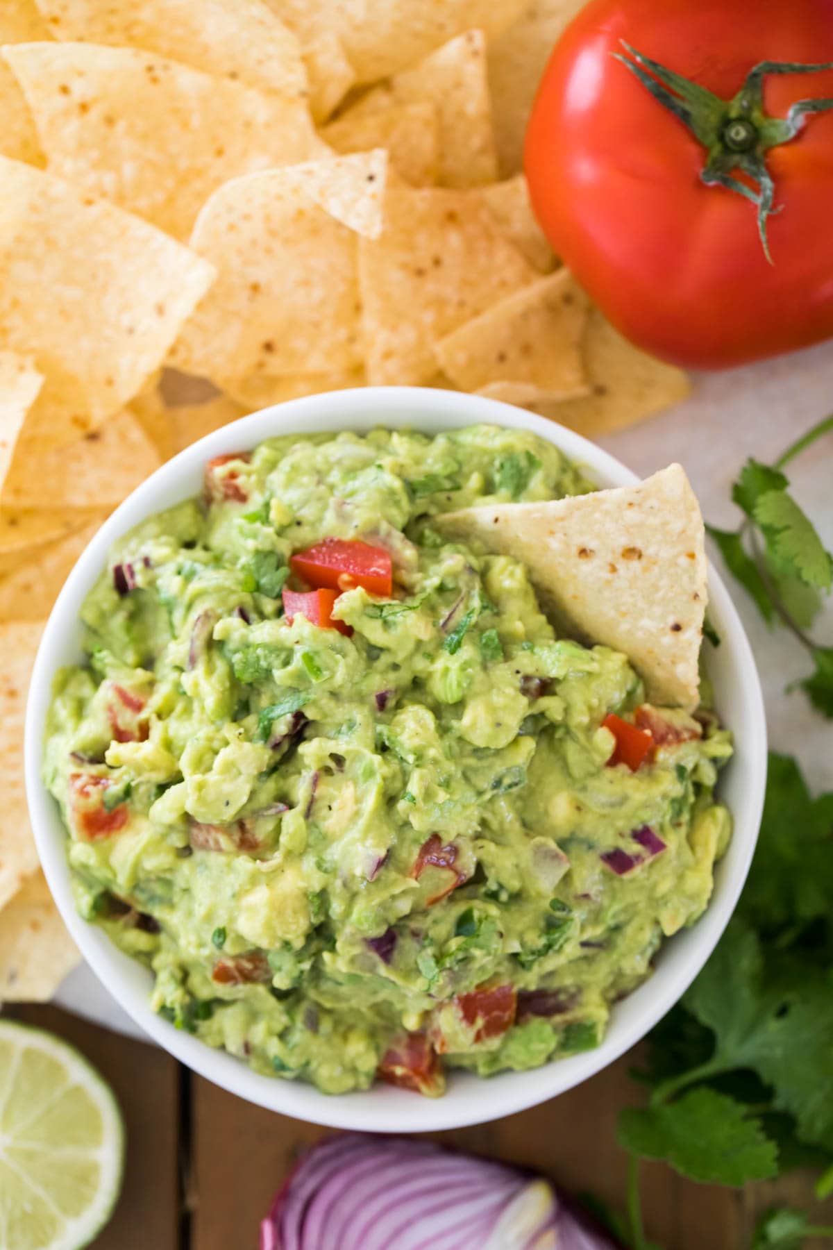 overhead view of guacamole in white bowl with chip