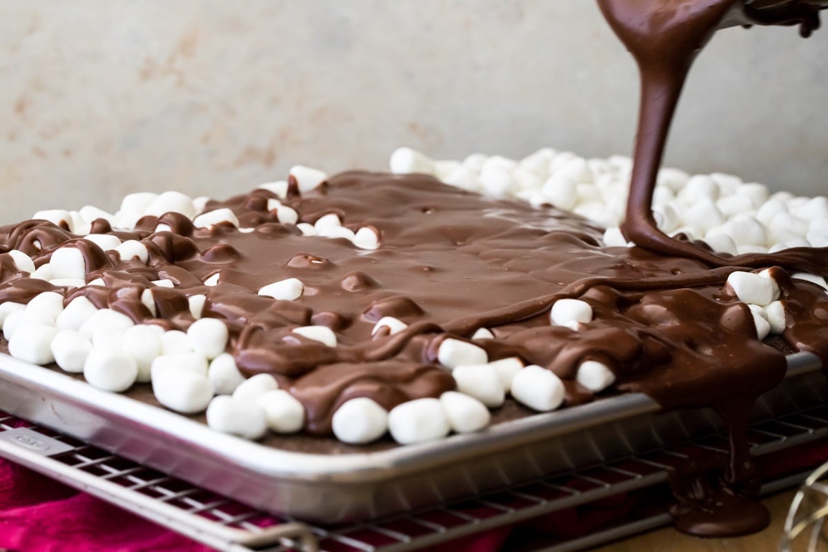 Pouring chocolate over cake covered in mini marshmallows