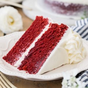 Slice of frosted Red Velvet cake on a white plate
