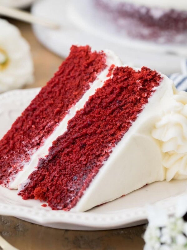 Slice of frosted Red Velvet cake on a white plate