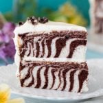 slice of striped zebra cake standing upright on white plate