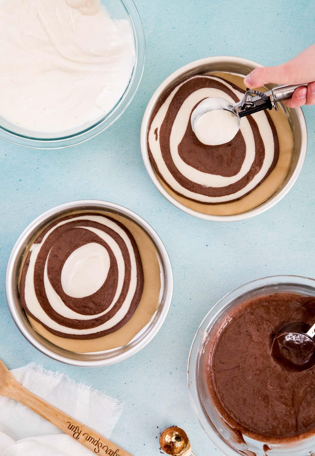 Portioning white and chocolate batter into cake tins for zebra cake