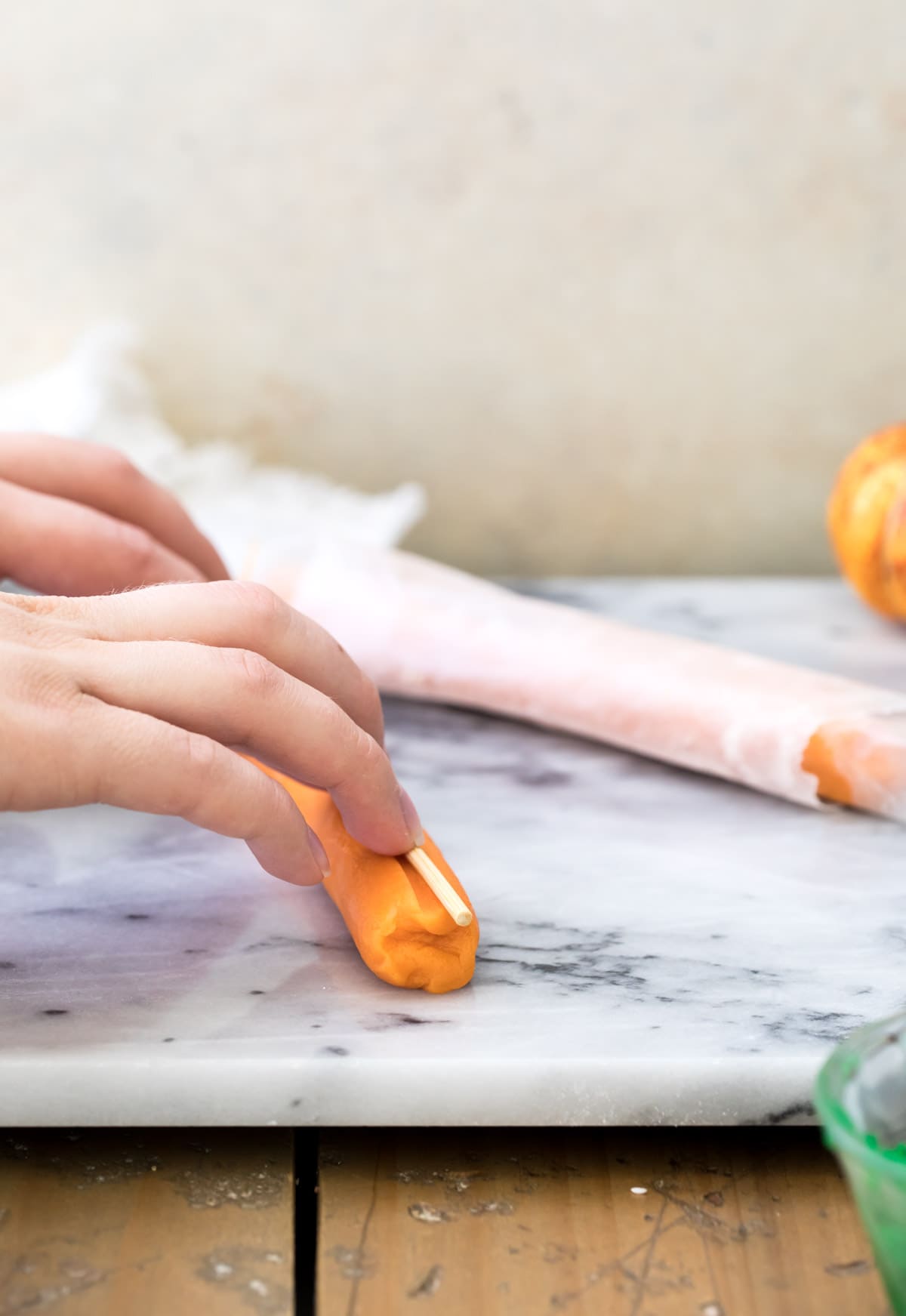 Pressing a wooden skewer into an orange log of cookie dough