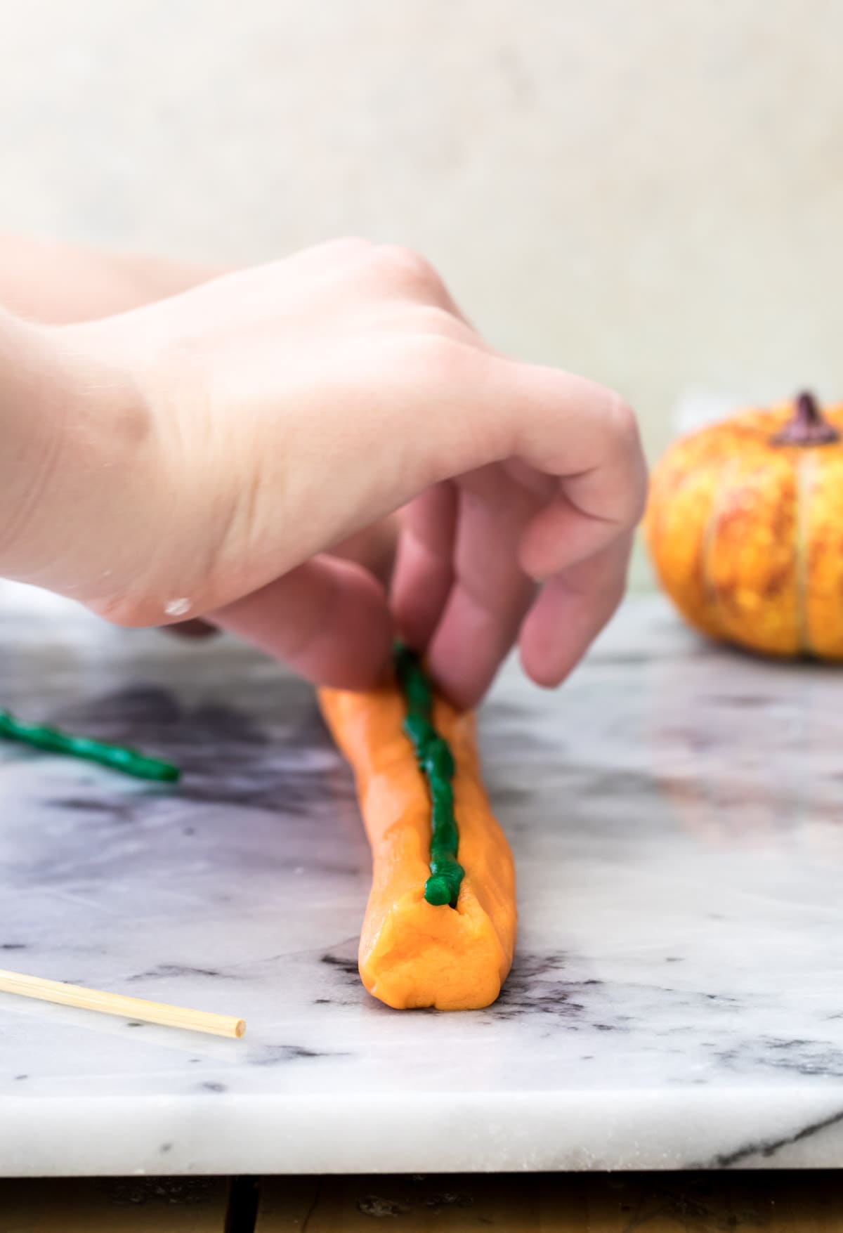 adding green cookie dough stem to pumpkin shaped cookie dough