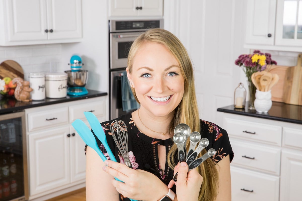 girl holding spatulas and measuring spoons