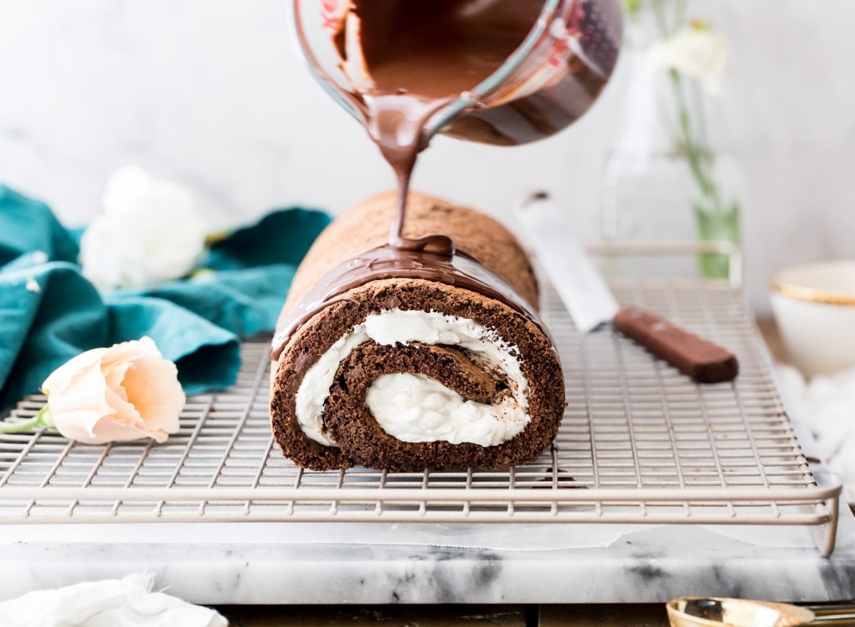 Pouring melted chocolate over swiss roll