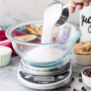 pouring sugar into glass bowl on digital scale