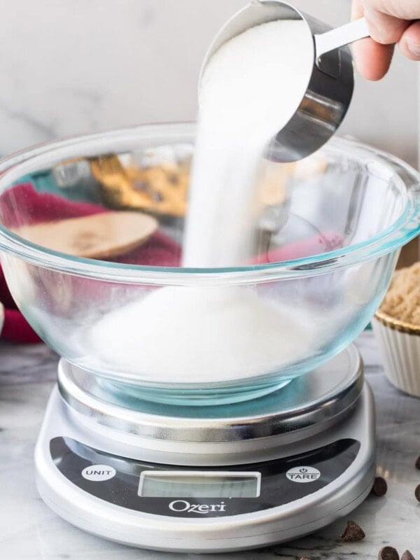 pouring sugar into glass bowl on digital scale