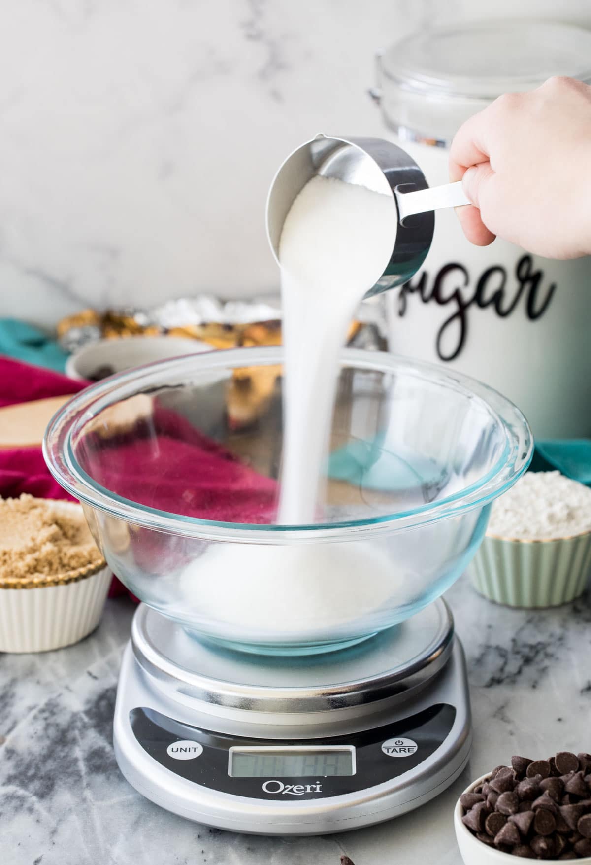 pouring sugar into glass bowl on digital scale