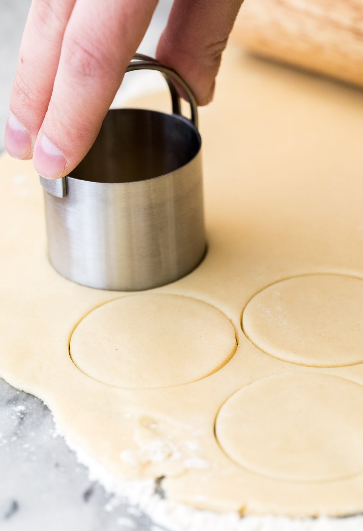 using biscuit cutter to cut out dough