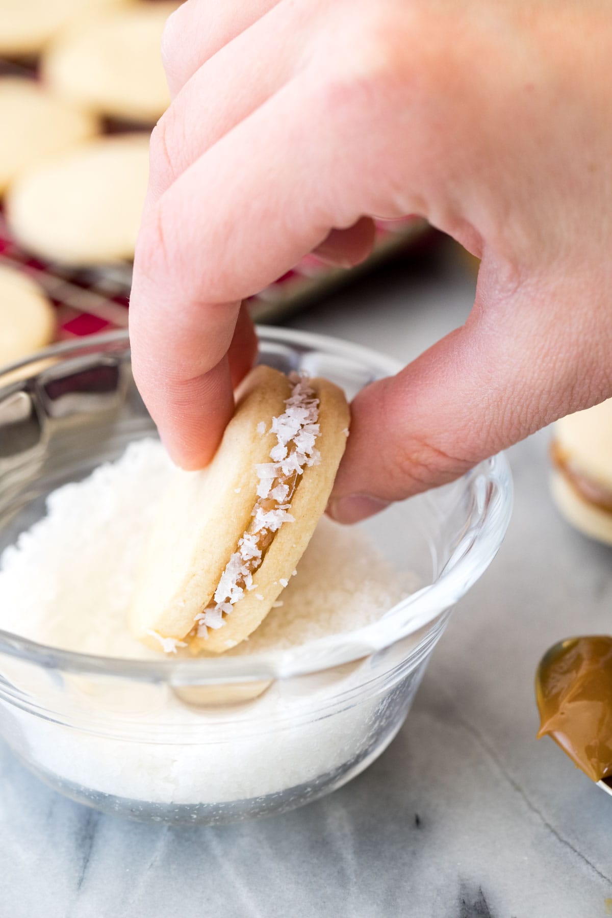 Dipping dulce de leche sandwich cookie in fine coconut