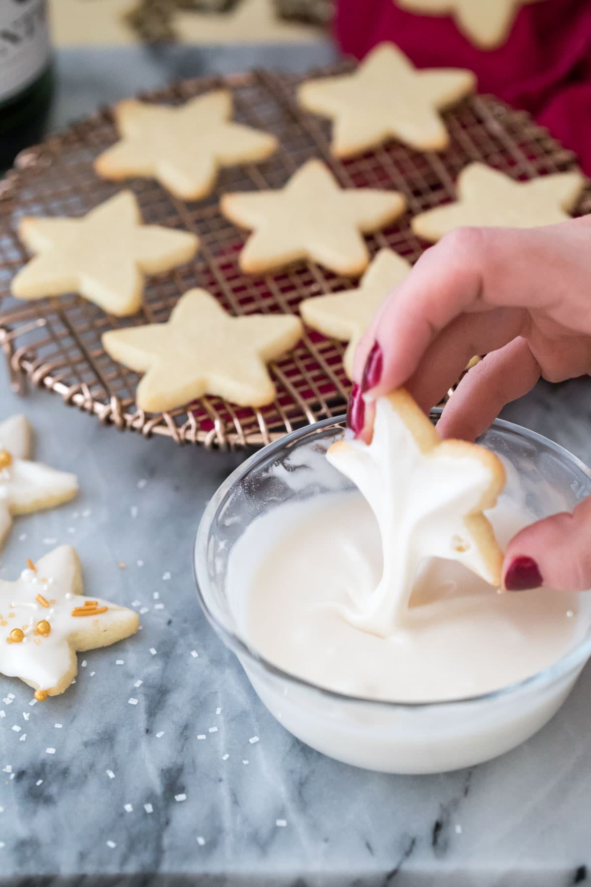 dipping a star-shaped cookie into champagne icing