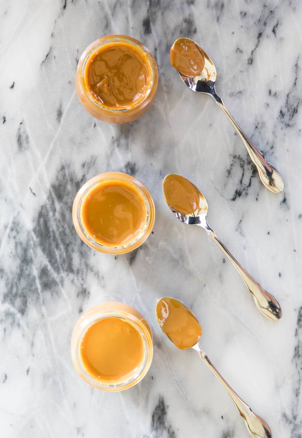 overhead of three jars of dulce de leche, each one darker than the one before it