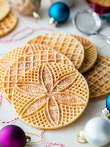 Pizzelle arranged on white board surrounded by ornaments