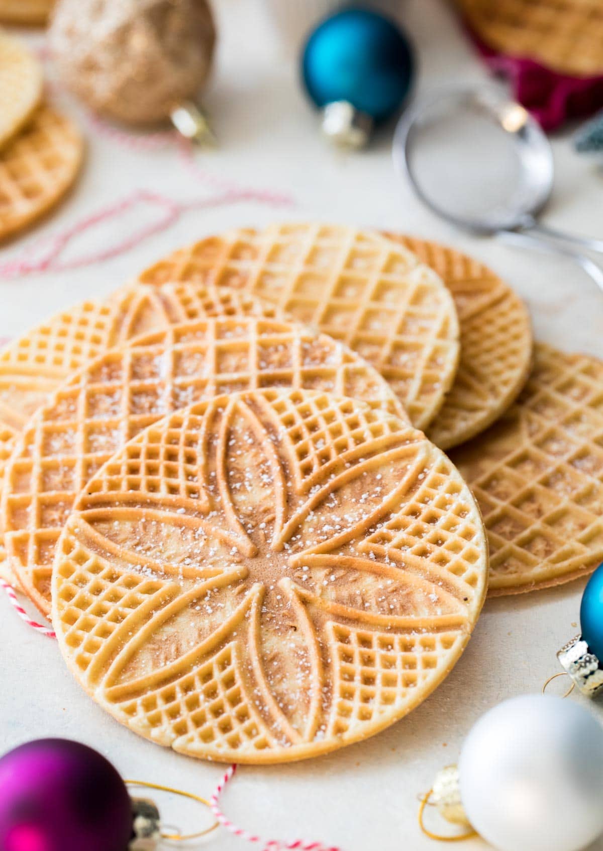 Pizzelle arranged on white board surrounded by ornaments