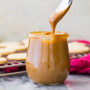 dipping spoon into jar of dulce de leche