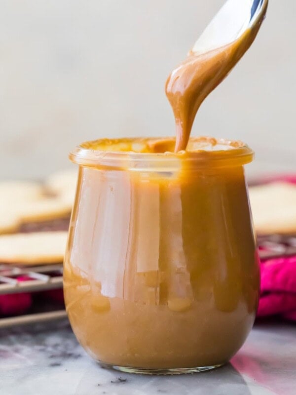 dipping spoon into jar of dulce de leche