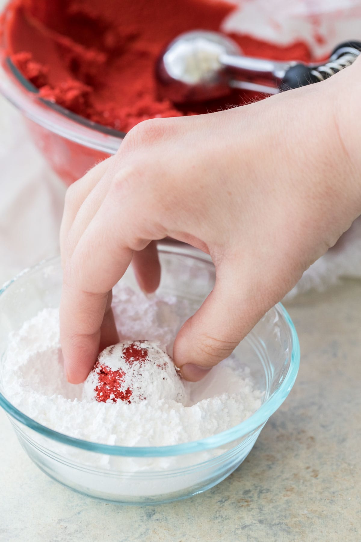 rolling red velvet cookie dough in powdered sugar