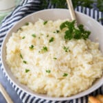 Creamy risotto in a white bowl sprinkled with parsley