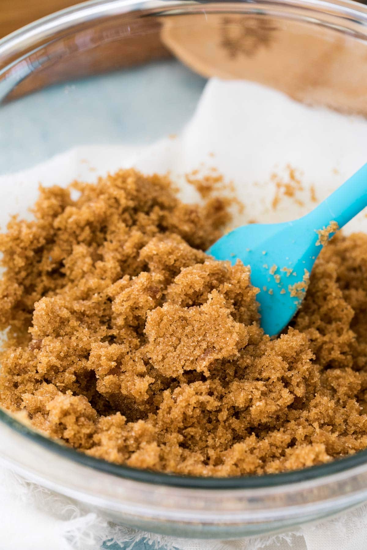 Closeup of brown sugar in a glass bowl with a blue spatula