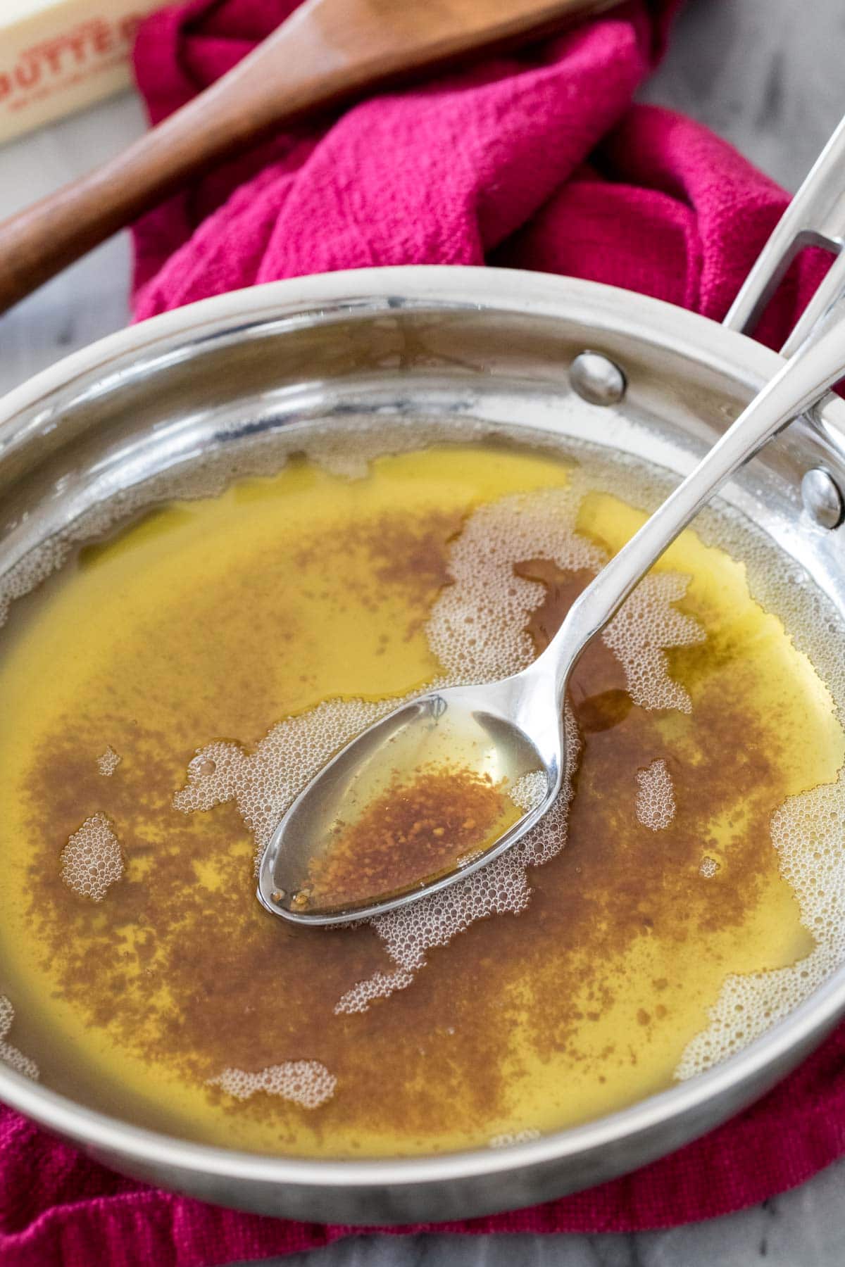 brown butter in saucepan with spoon showing browned bits