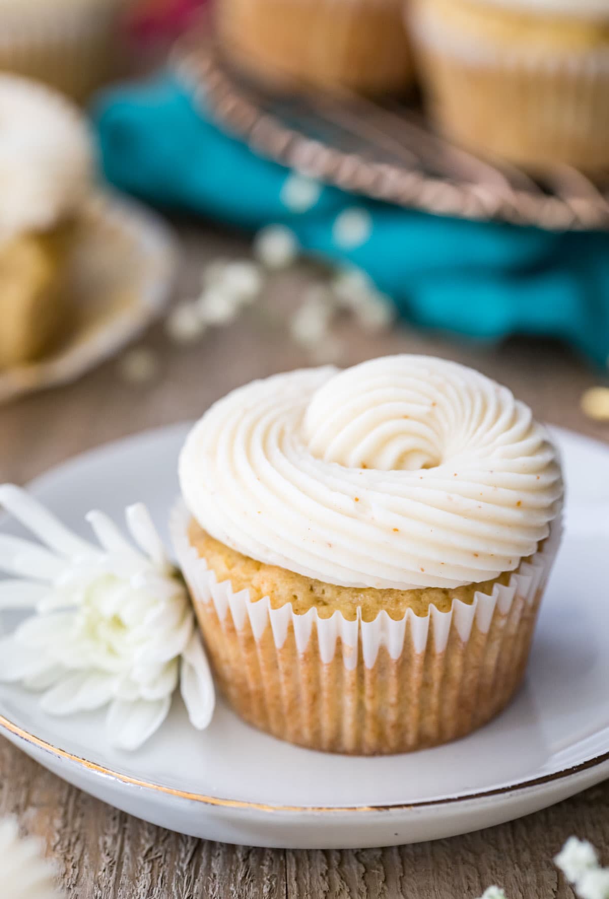 Banana cupcake on a white plate next to a white flower.