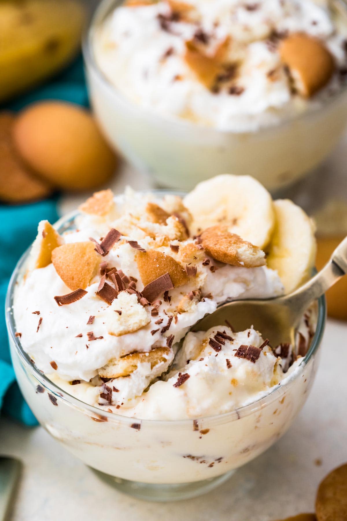 Closeup of banana pudding with a spoon in a clear glass bowl