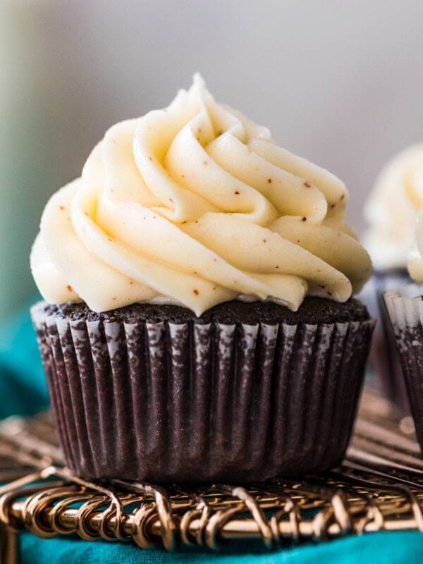 chocolate cupcake in a white liner topped with a pile of piped brown butter frosting