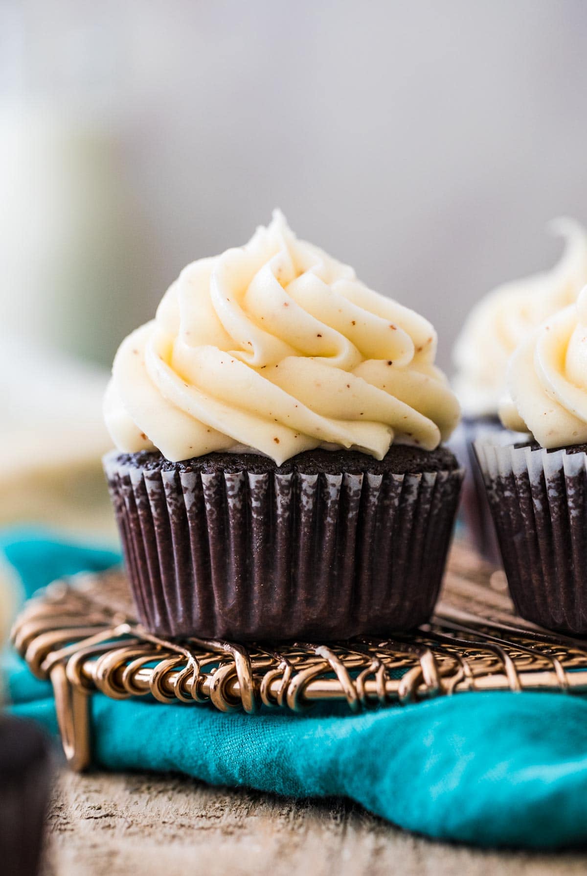 chocolate cupcake in a white liner topped with a pile of piped brown butter frosting