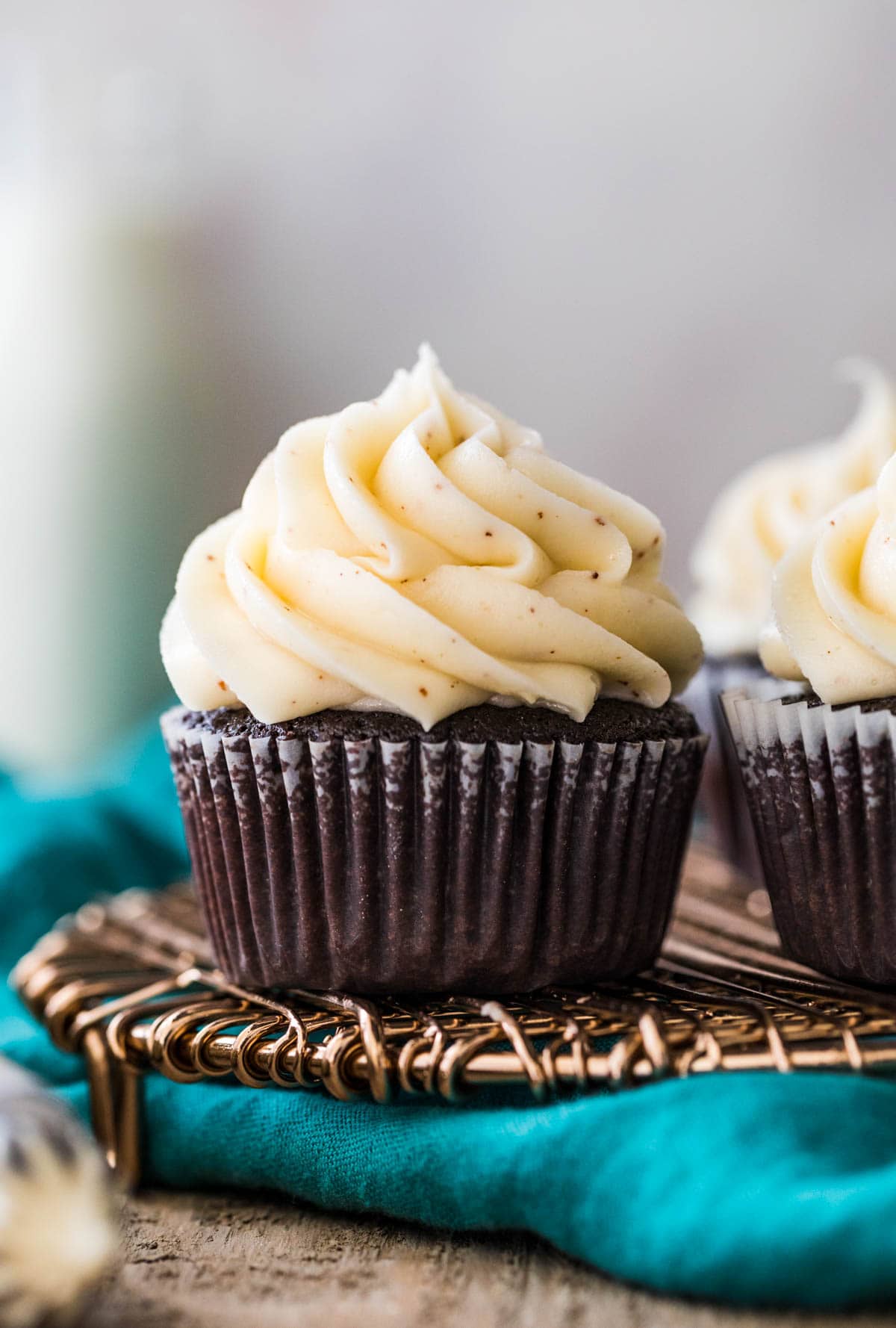 chocolate cupcake in a white liner topped with a pile of piped brown butter frosting