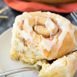 Closeup of orange sweet roll on white plate with a fork
