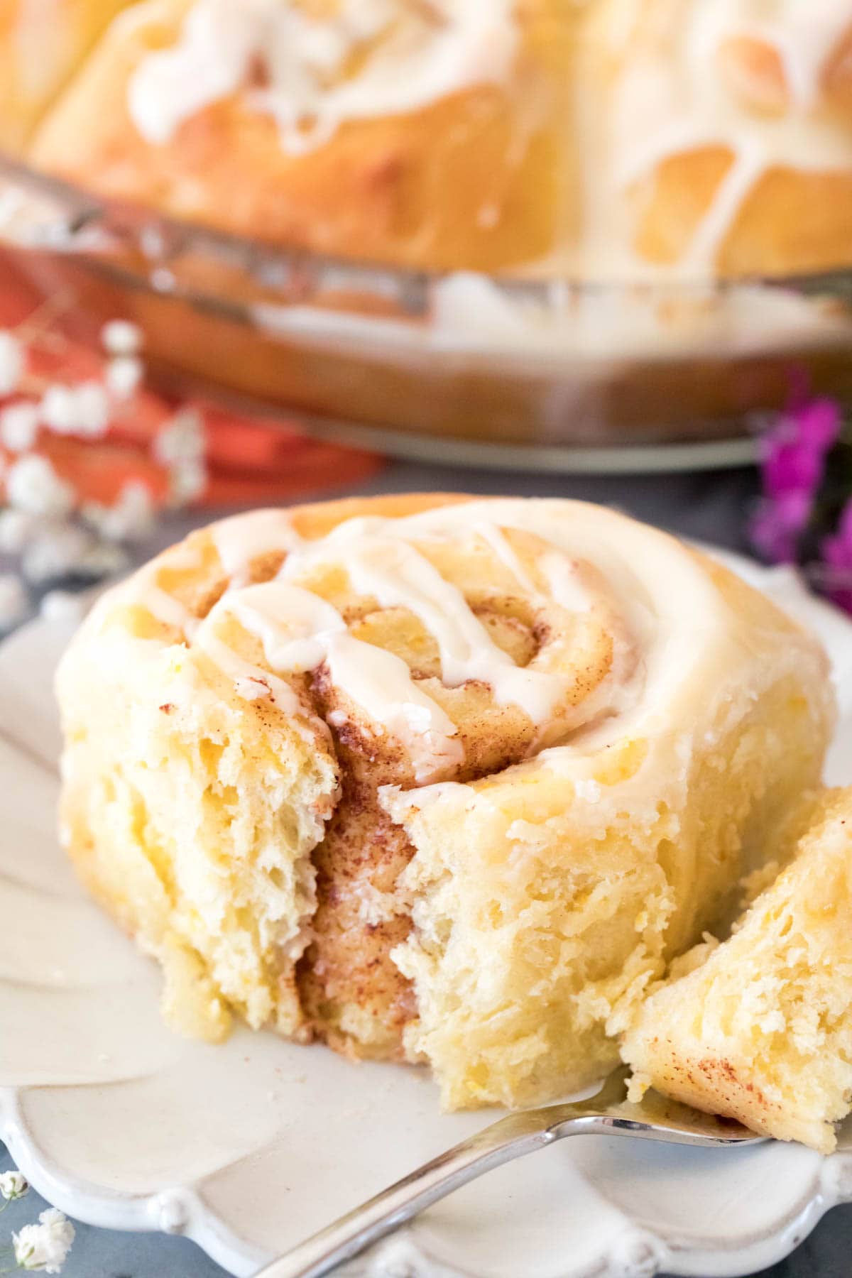 Closeup of iced orange sweet roll on a white plate