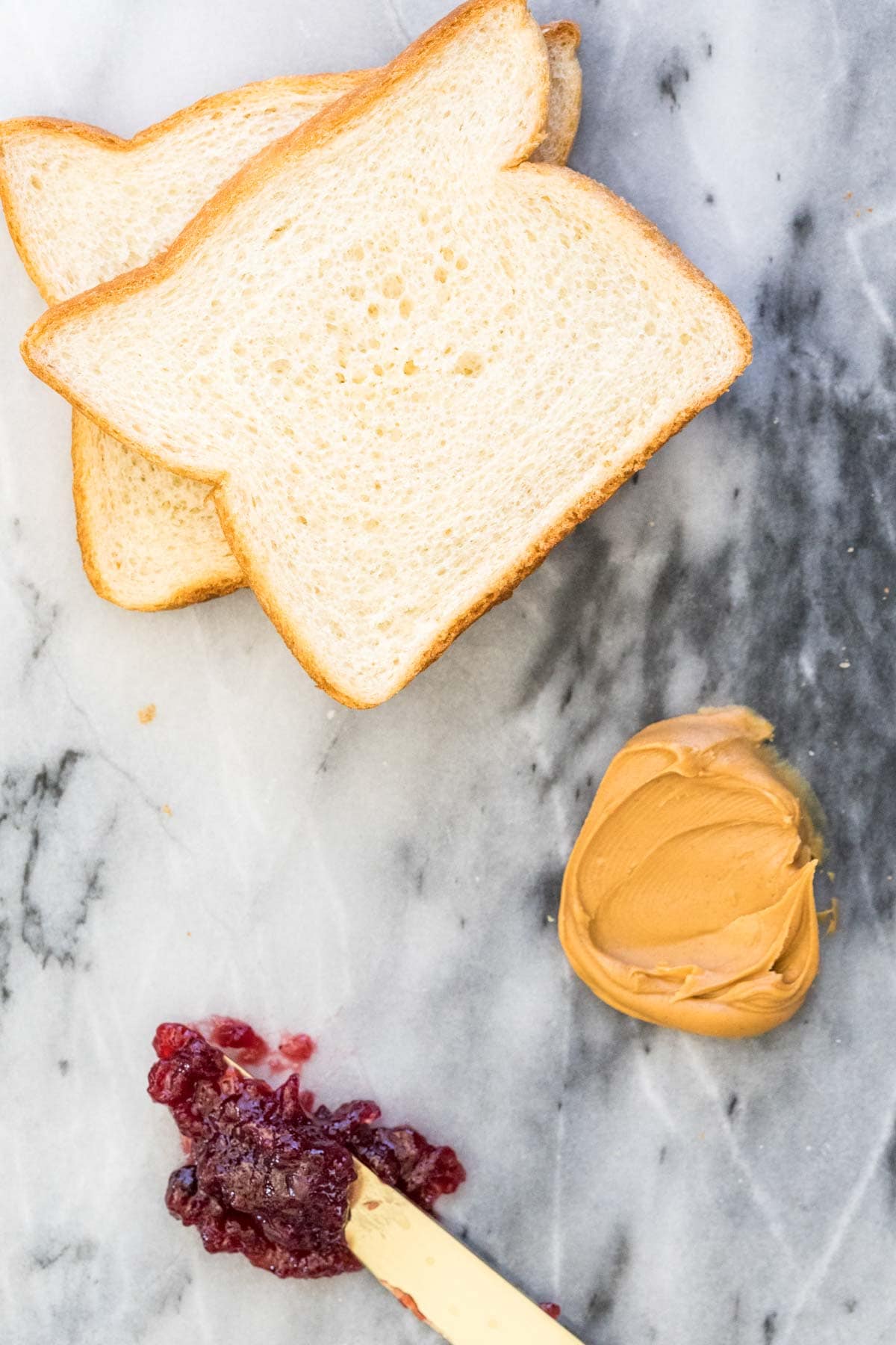 bread, peanut butter, and jelly on a marble board