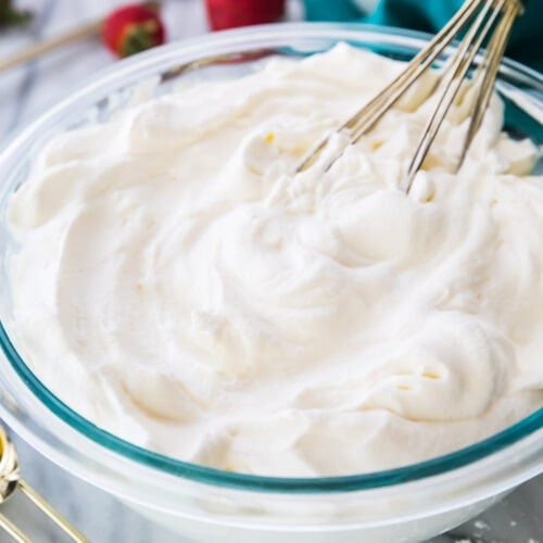 Bowl of whipped cream with a whisk.