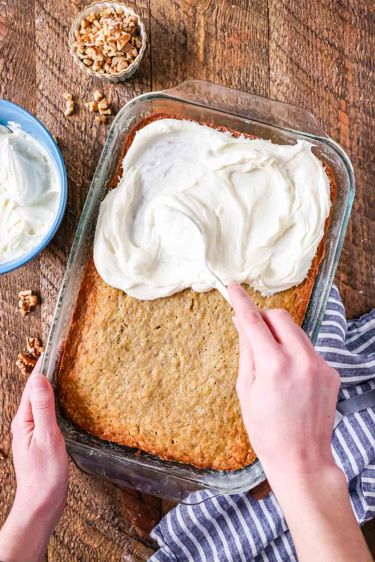 Spreading silky cream cheese frosting over a golden brown pan of banana cake.