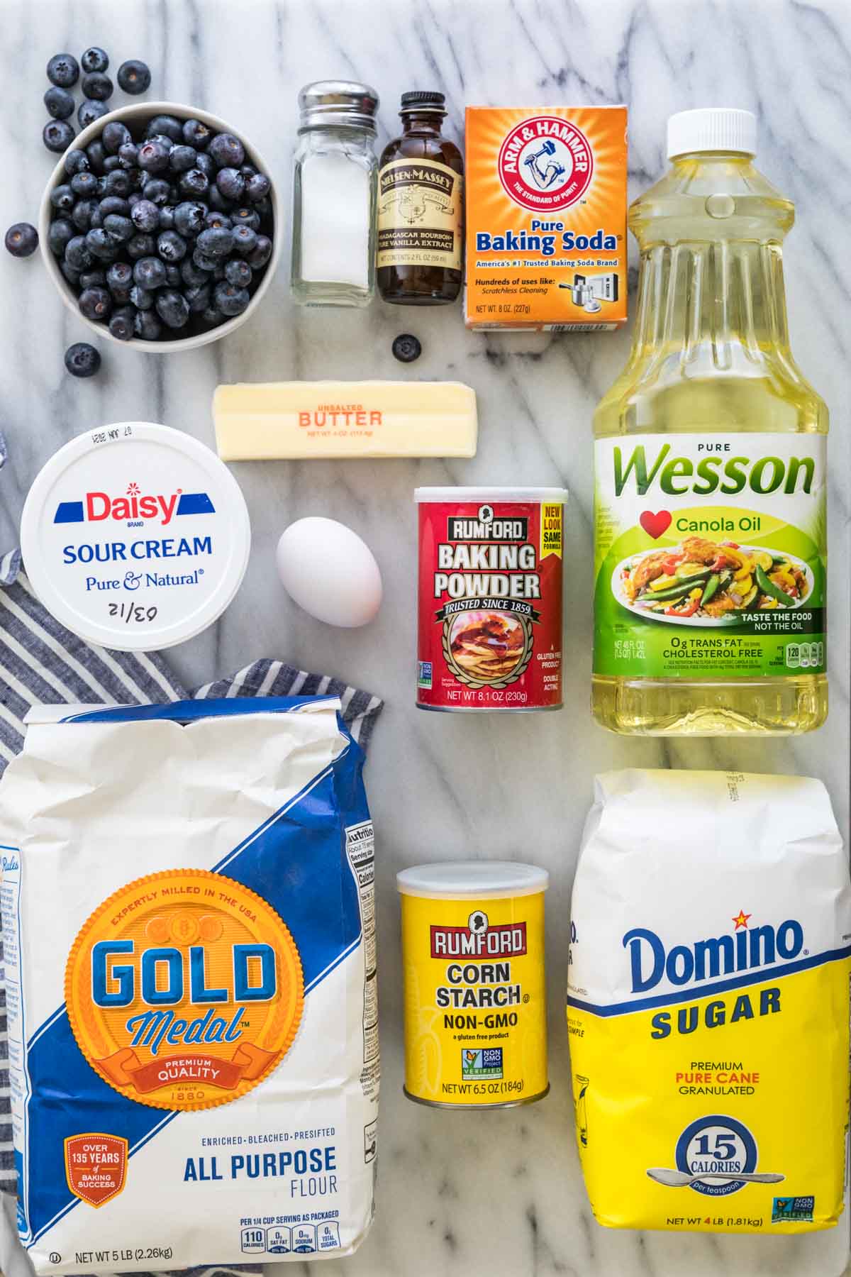 Ingredients for blueberry muffins: flour, cornstarch, sugar, canola oil, bakin gpowder, egg, sour cream, butter, baking soda, vanilla, salt, blueberries