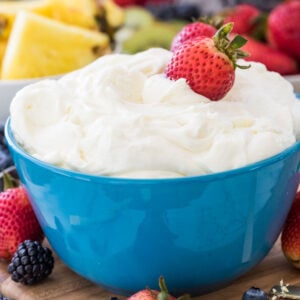 Fruit dip in a blue bowl with strawberries in it.