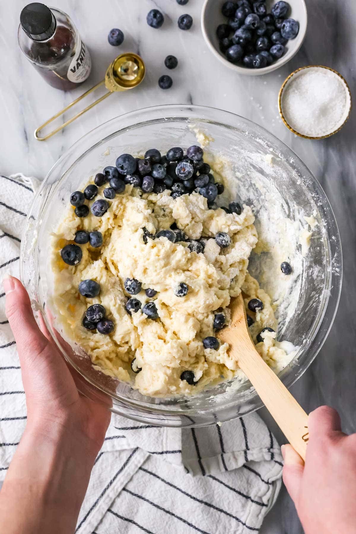 Mixing muffin batter to make blueberry muffins, folding in the blueberries.