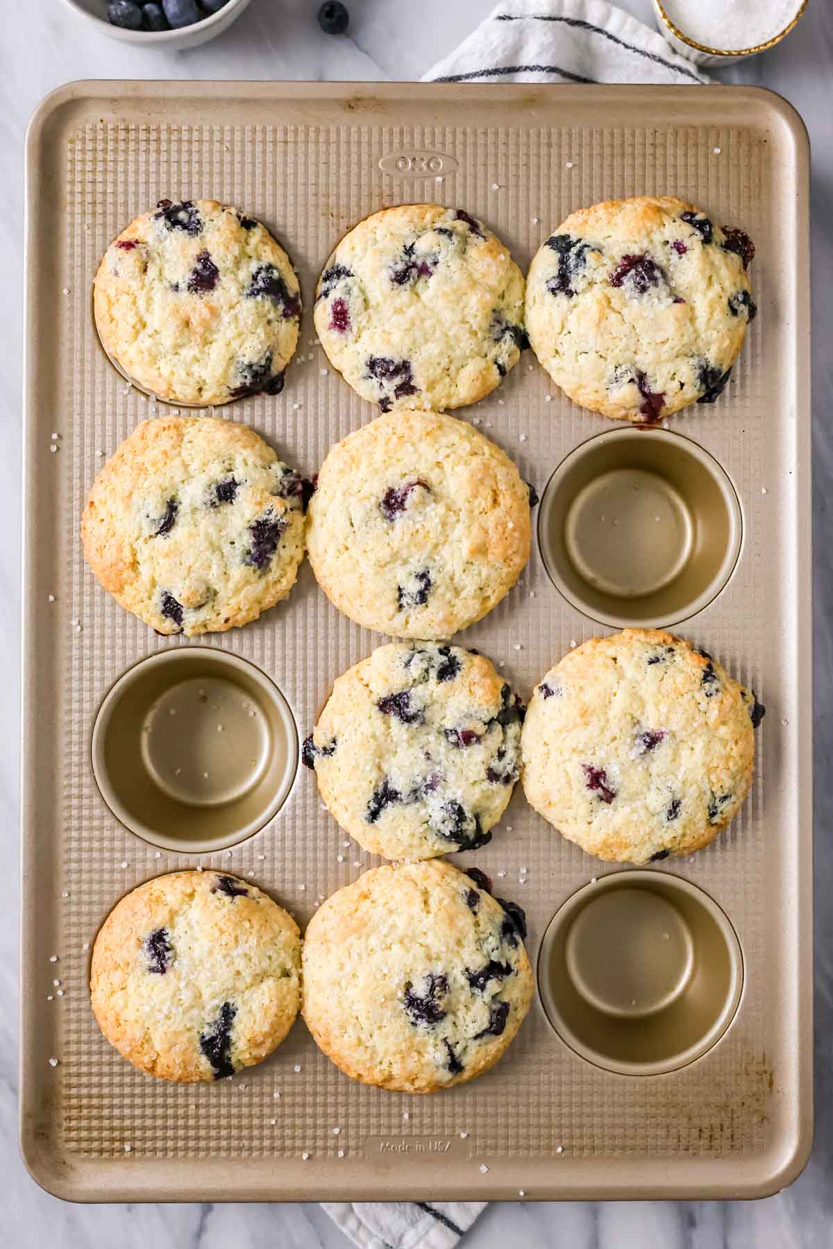 Overhead of 9 baked blueberry muffins in muffin tray.