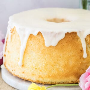 Golden chiffon cake with white glaze surrounded by a pink and yellow flower