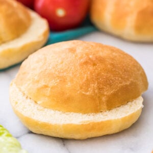 sliced potato bun on marble with lettuce and more buns in background