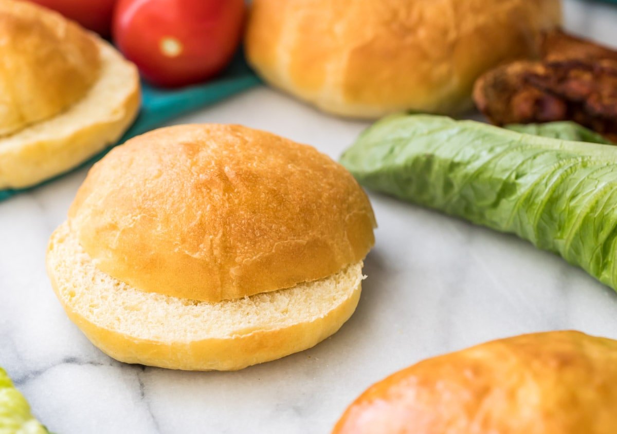 sliced potato bun on marble with lettuce and more buns in background