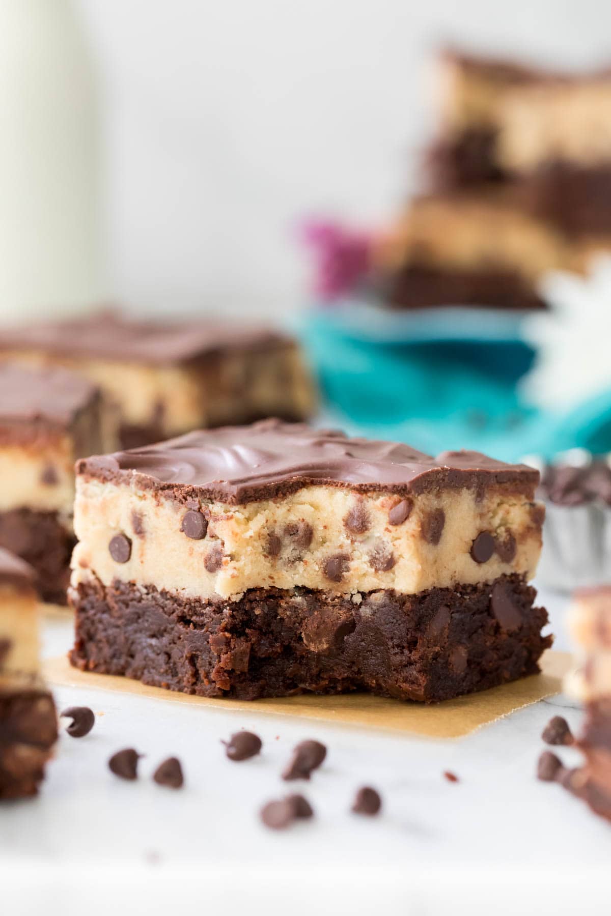 A cookie dough brownie with a bite missing surrounded by more brownies and mini chocolate chips