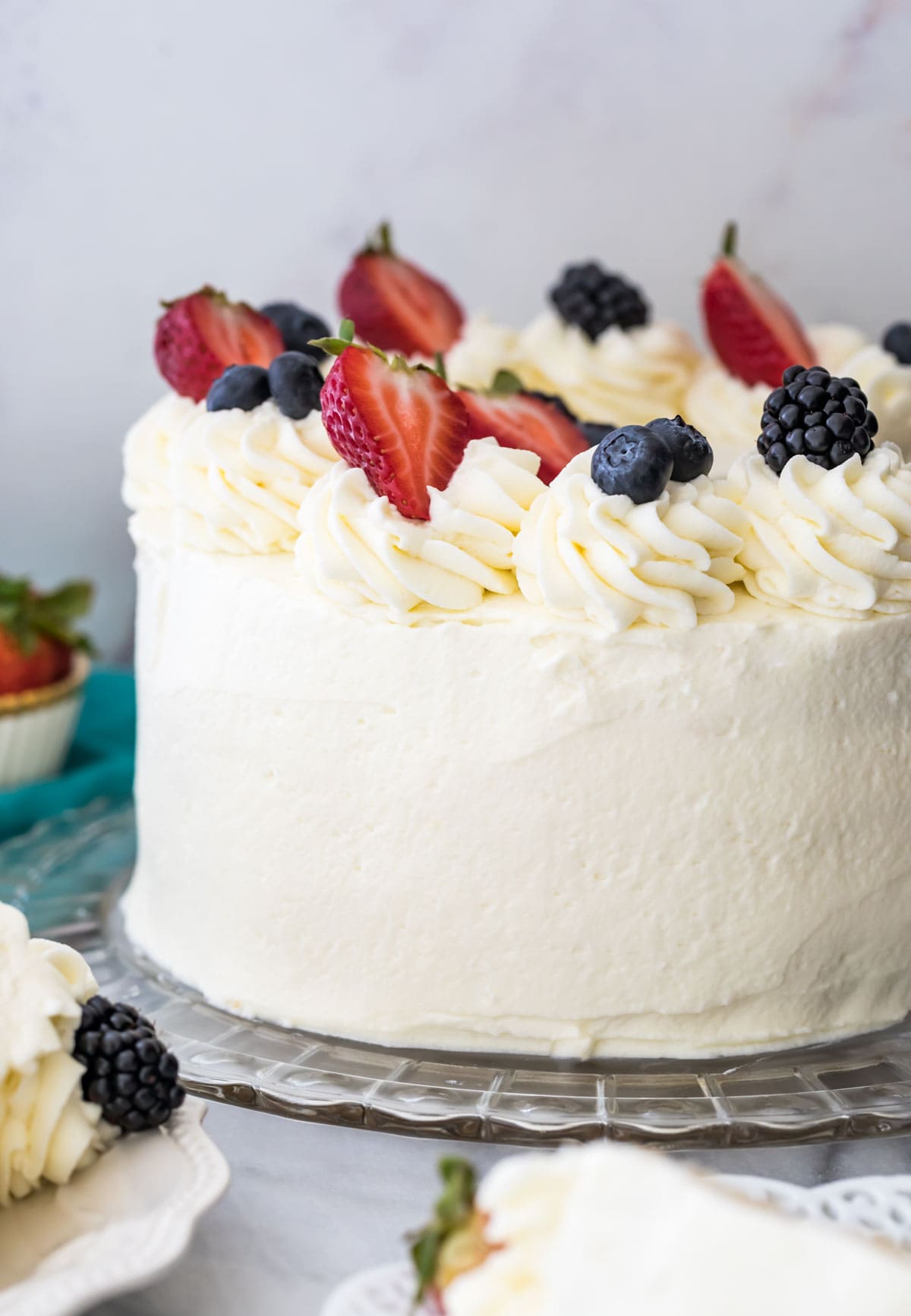 Chantilly cake on a glass platter, topped with fresh fruit