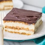 Slice of eclair cake showing two layers of pastry cream on a white plate with a teal towel beneath the plate