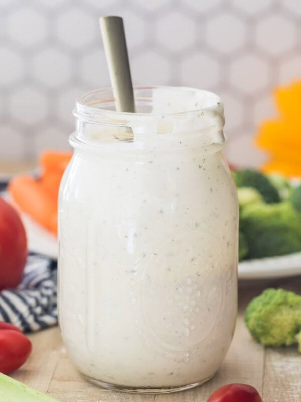 mason jar full of ranch dressing centered in photo with honeycomb tile background and fresh veggies surrounding jar