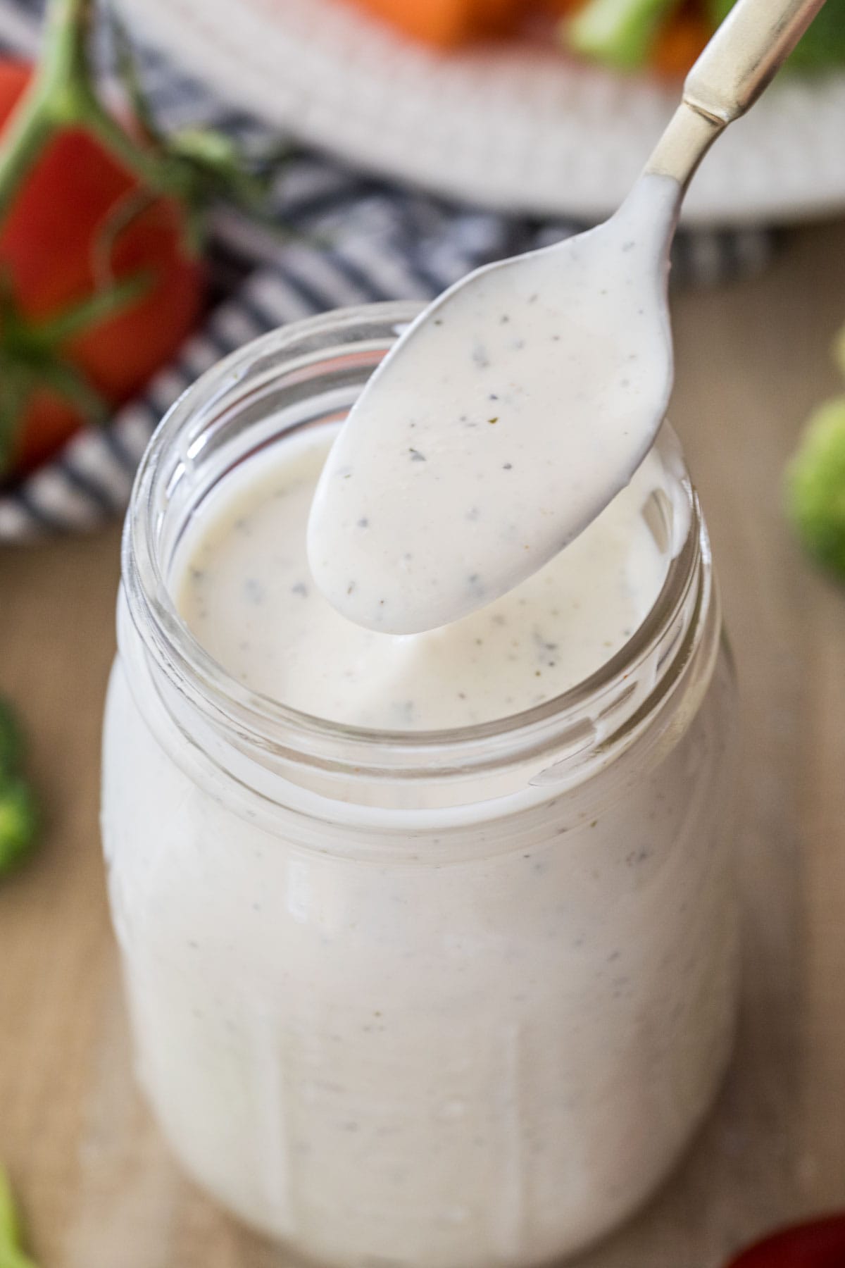 spoonful of homemade ranch being held over mason jar of ranch